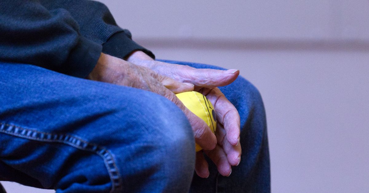Elderly person holding a yellow stress ball in denim jeans, symbolizing relaxation and comfort.