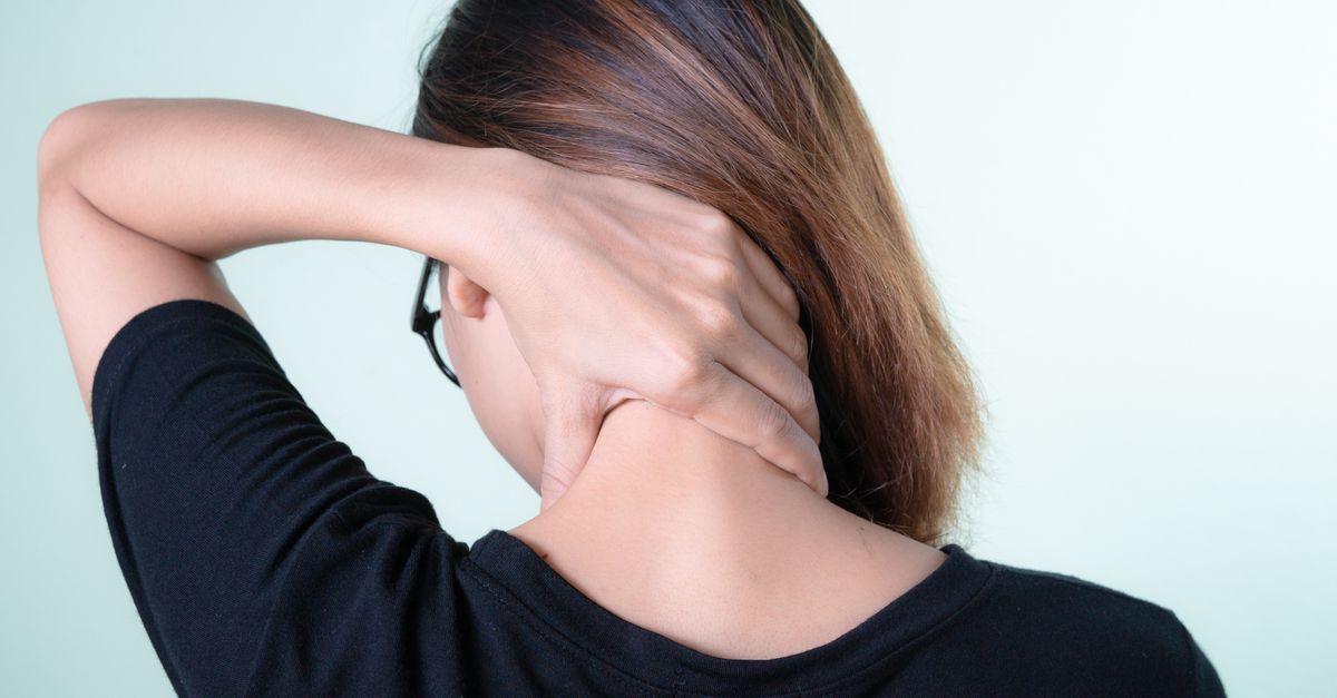 Rear view of a woman massaging her neck, depicting neck pain relief and self-care.