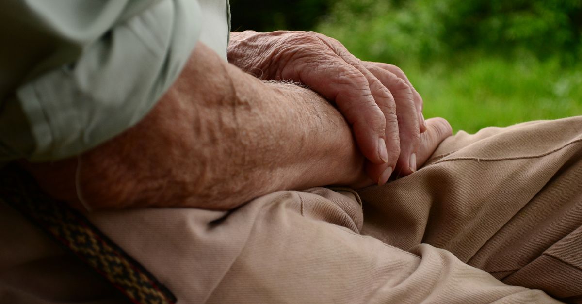 Close-up of a senior's hands resting peacefully on a lap, conveying quiet contemplation.
