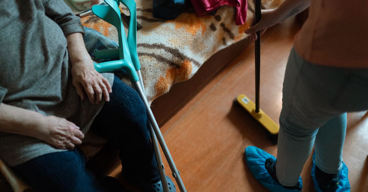A caregiver helping an elderly woman at home, showing home care support.