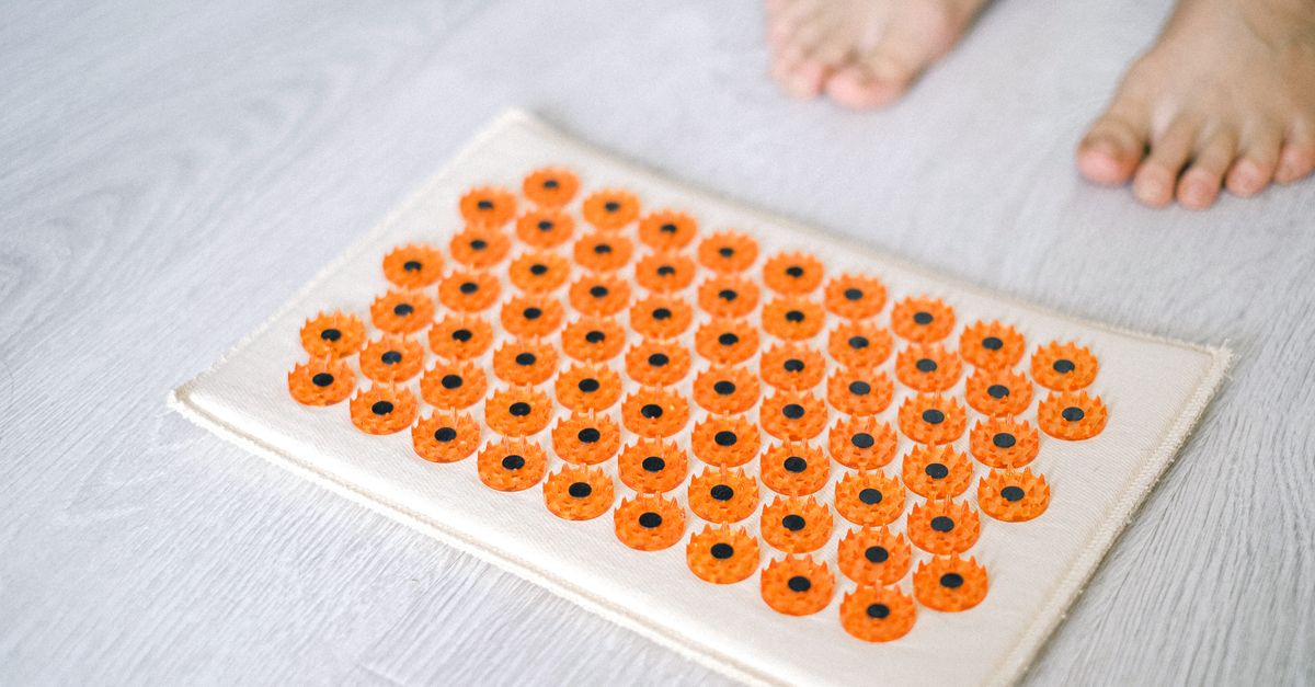 Close-up of a foot acupressure mat on a wooden floor, ideal for relaxation therapies.