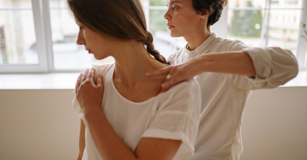 A massage therapist providing shoulder treatment to a client in a calm indoor setting.