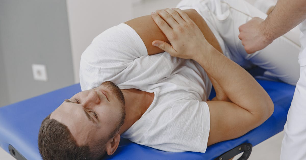 A man undergoing a therapeutic massage session on a blue massage table in a clinic.
