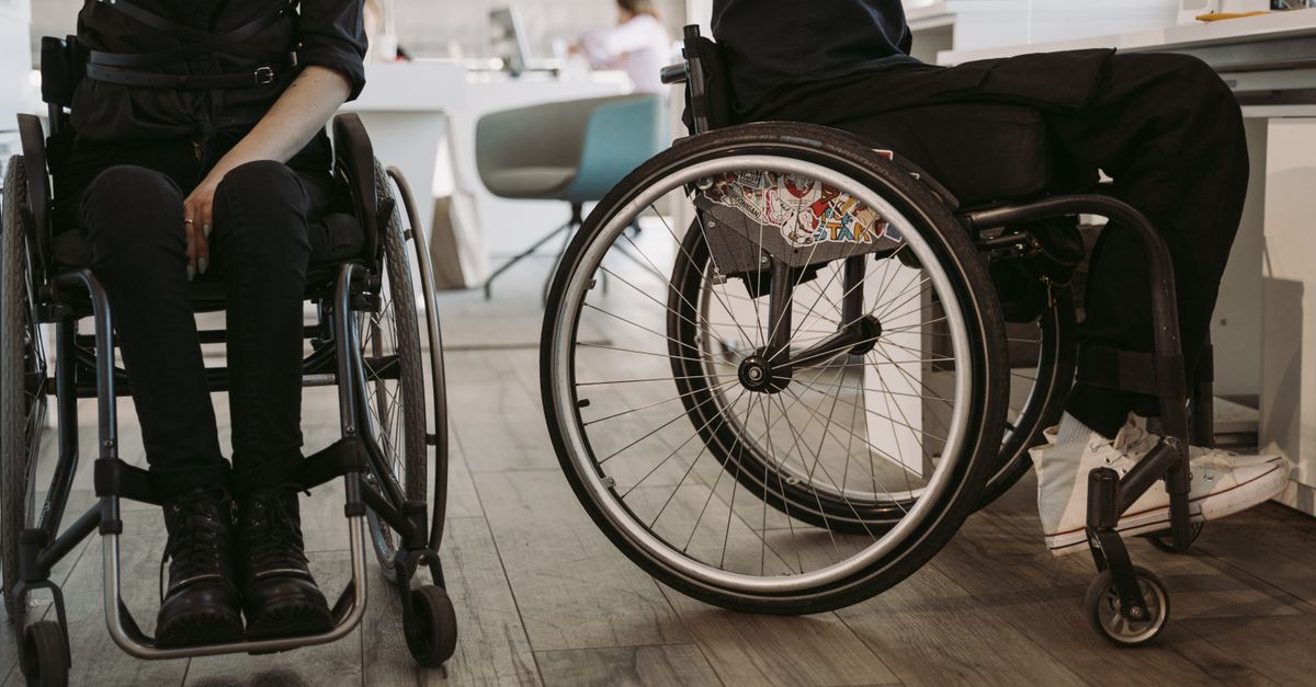 Two people in wheelchairs, indoors, symbolizing accessibility and modern workplace diversity.