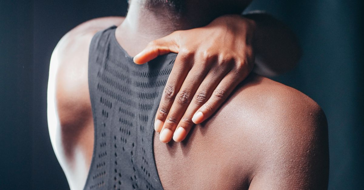 A close-up of a person touching the side of their neck and shoulder.