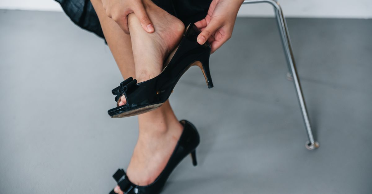 Close-up of a woman removing black high heels while seated indoors.