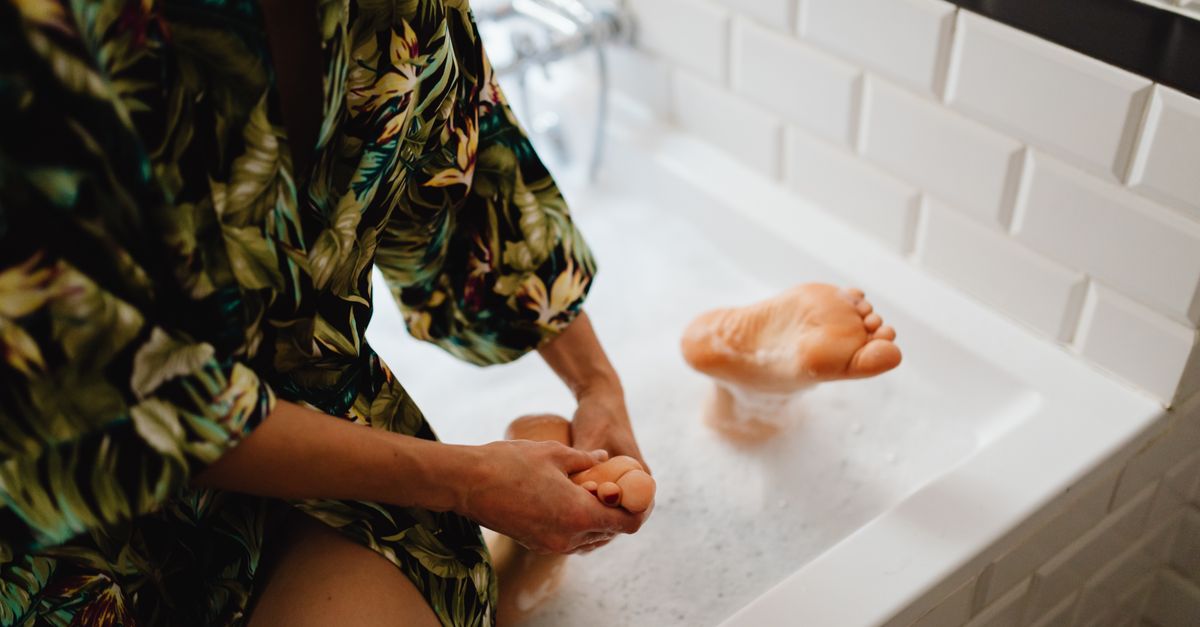 Indulge in a relaxing foot massage while enjoying a bubble bath in a serene bathroom environment.