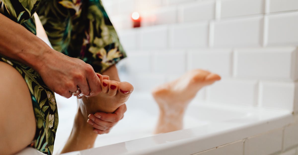 A soothing foot massage being given in a bath with white tiled walls and a relaxed atmosphere.