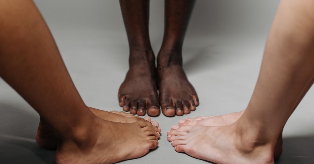 Close-up of diverse adult feet on a neutral background symbolizing unity.