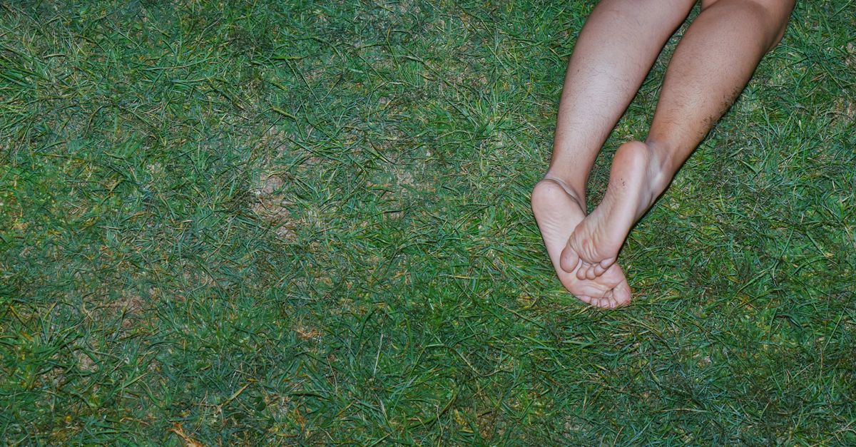 A person resting outdoors, showing bare legs and feet, conveying relaxation.