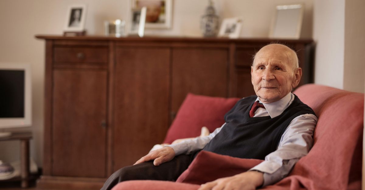 Senior man sitting comfortably on a sofa in a warm and inviting living room.