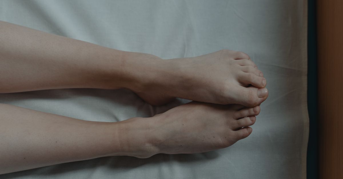 A close-up of bare feet resting on white sheets, conveying solitude and tranquility.