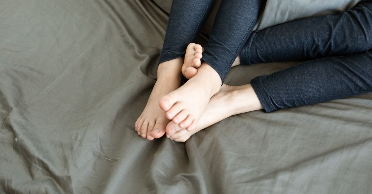 Feet resting on a bed in comfortable clothing, showing relaxation and comfort.