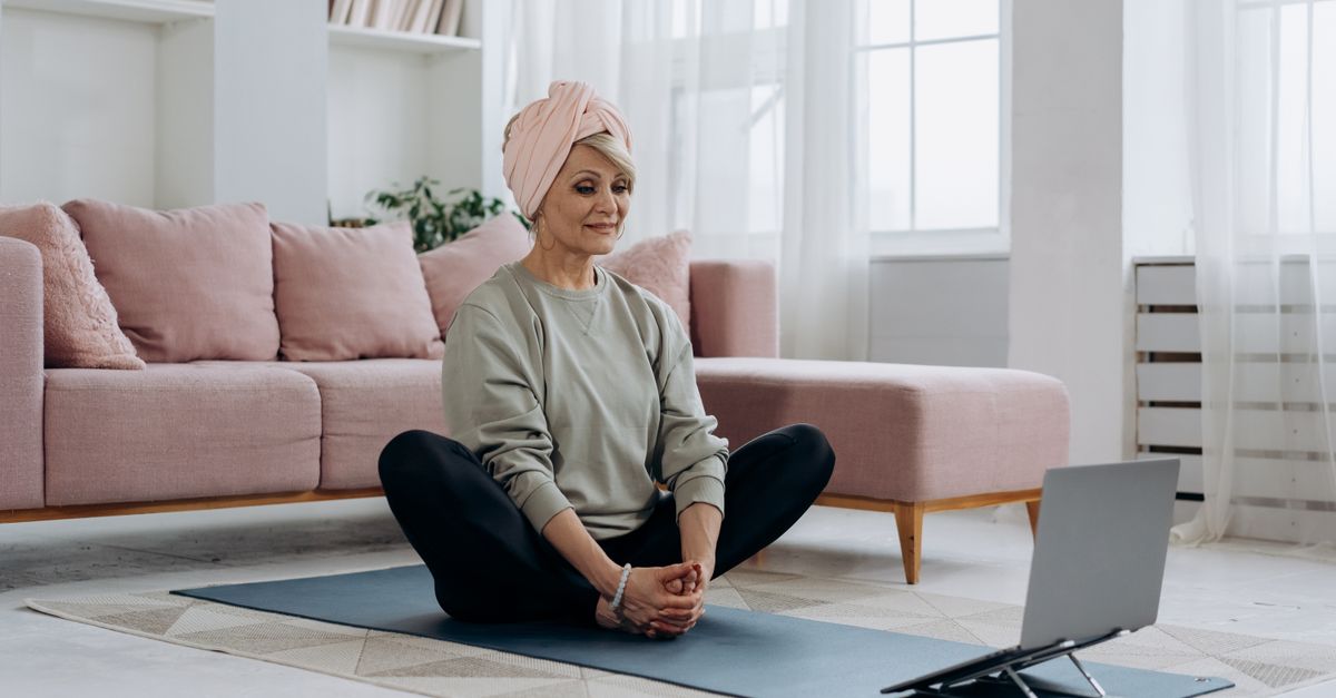 Elderly woman sitting on a mat indoors during a gentle daily routine.