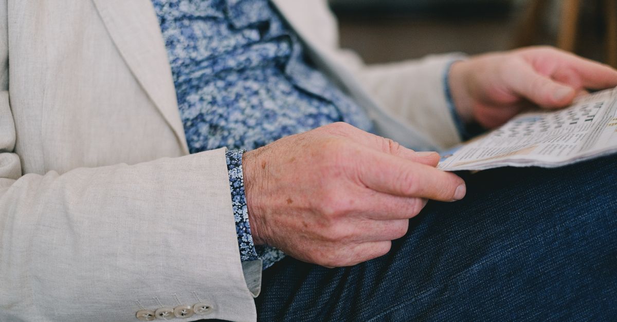 Close-up of a senior adult's hand holding a newspaper in a calm setting.