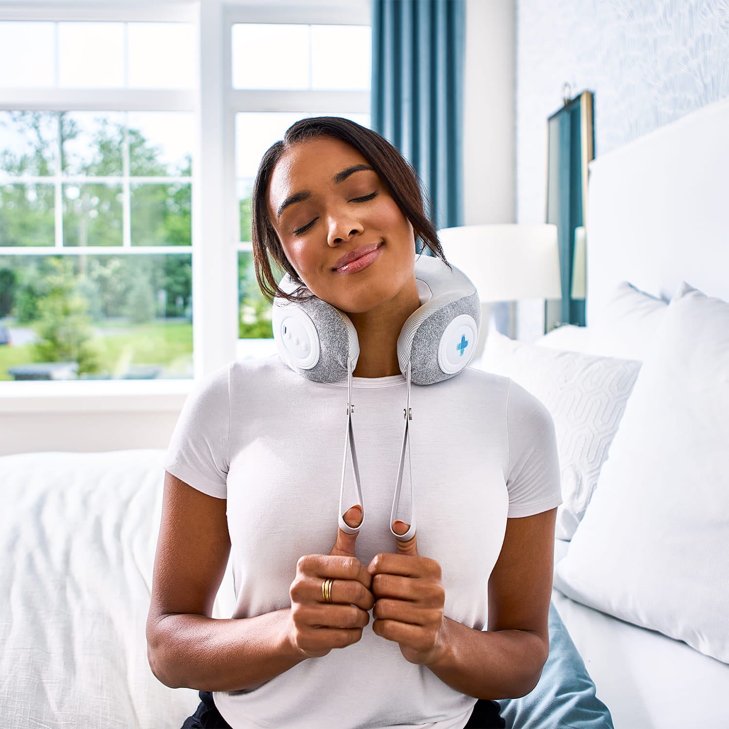 Woman using a neck massager in a bright living room